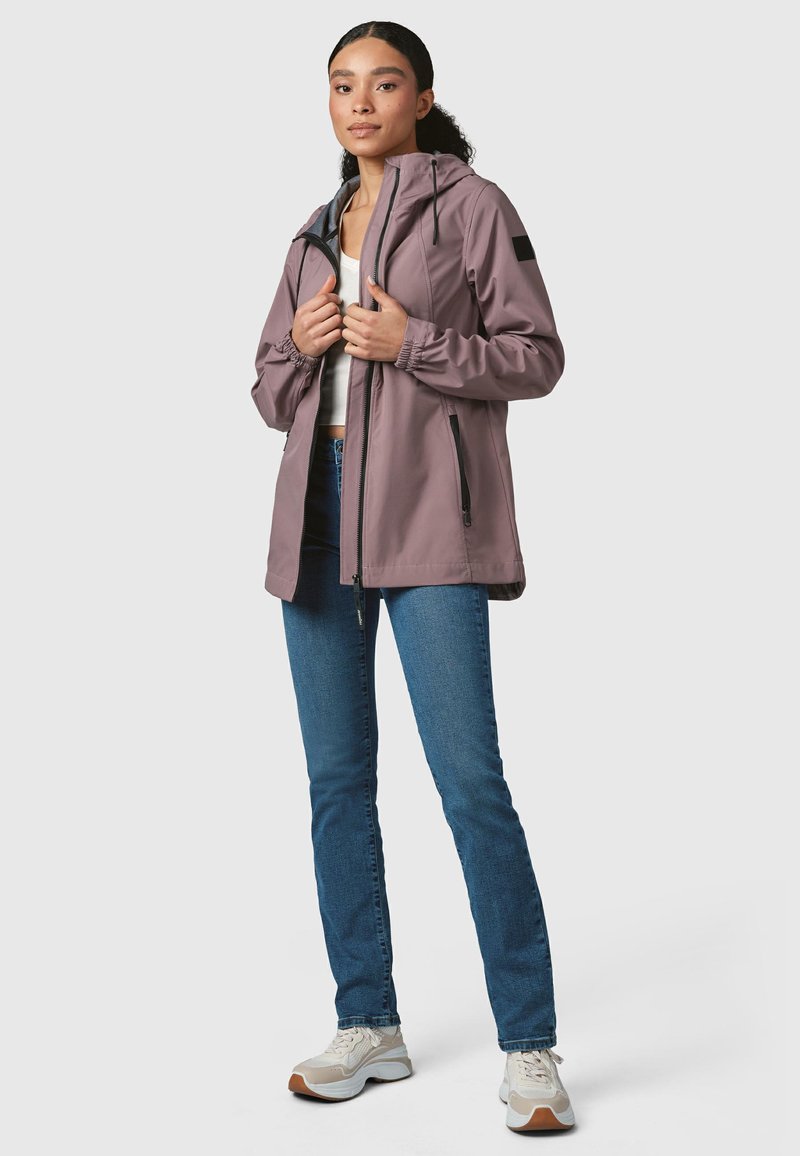 Světlá mauve voděodolná bunda se zipem vpředu, nastavitelnou kapucí a elastickými manžetami, kombinovaná s modrými džíny a neutrálními teniskami.