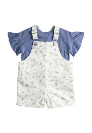 Camicia blu a maniche corte con volant abbinata a salopette corta bianca con stampa floreale, dotata di tasca frontale e spalline regolabili.