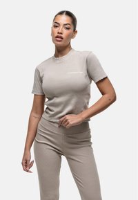 Top corto a coste beige con maniche corte e orlo grezzo, con il logo "GOODFORNOTHING" in bianco sul davanti. Pantaloni abbinati.