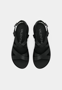 Czarne sandały z paskiem krzyżowym, regulowaną klamrą przy kostce, gładką matową teksturą i detalem z logo na wkładce.