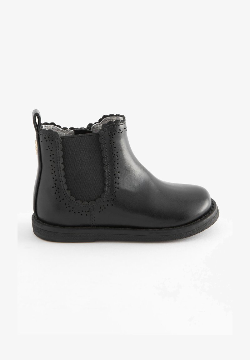 Stivale alla caviglia in pelle nera con bordi ondulati, dettagli perforati, pannelli elastici laterali e una linguetta sul retro. Texture liscia.