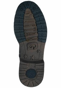 Black rubber sole with a textured pattern, featuring the word "MUSTANG" and stars. Tread design for grip is prominent.