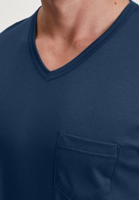 Navyblauwe V-hals T-shirt van zachte stof, met een borstzak en stikdetails op de halslijn. Gladde textuur, casual ontwerp.