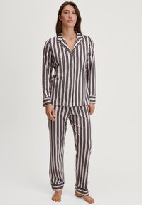 Gestreept pyjama-set met lange mouwen en broek. Gemaakt van zachte stof met verticale zwarte, rode en witte strepen; knoopsluiting op het shirt.