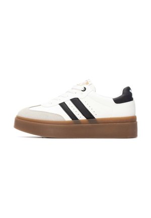 Zapatilla blanca con rayas negras, con punta redondeada y suela gruesa de goma marrón. Detalles texturizados en la punta y el talón.
