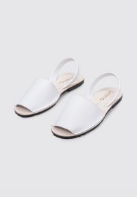 Sandalias blancas de punta abierta con un exterior liso, diseño minimalista, correas ajustables dobles y una suela de goma negra texturizada.