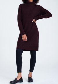 Burgundy stickad klänning med hög polokrage, ribbade ärmslut och nederkant. Kombinerad med svarta leggings och slip-on skor.