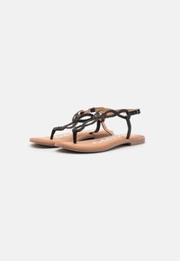 Sandalias de tiras trenzadas negras con una plantilla acolchada marrón, que cuentan con una delgada correa para el tobillo y una suela plana para mayor comodidad.