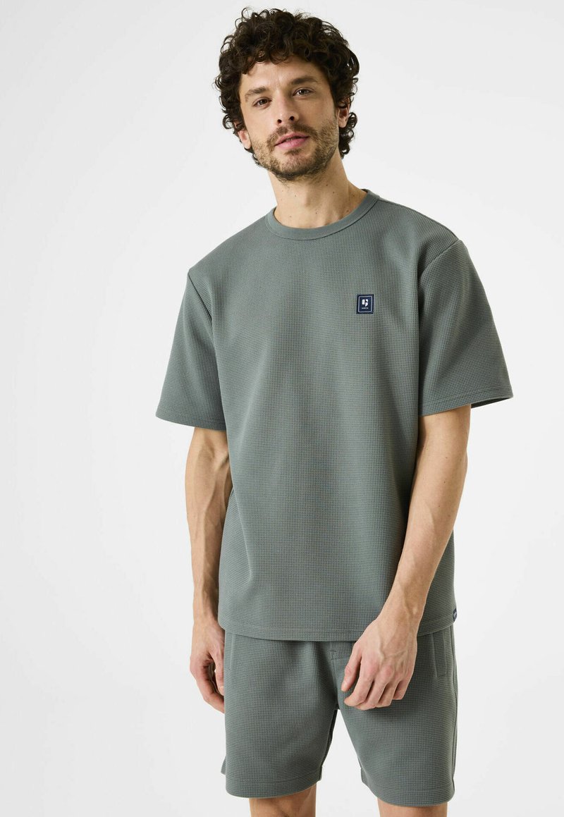 Grijze katoenen t-shirt met wafelstructuur en bijpassende shorts, ronde halslijn, korte mouwen en een klein logo-opdruk op de borst.