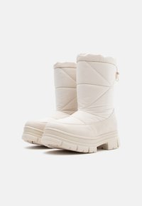 Botine de iarnă bej, căptușite, cu o textură matlasată, vârf rotund, tălpi groase și un sistem de tragere în spate pentru o îmbrăcare ușoară.