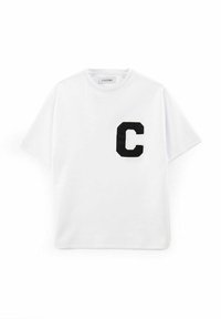 Hvit kortermet T-skjorte laget av bomull, med en svart brodert bokstav "C" på venstre side. Rund hals og avslappet passform.