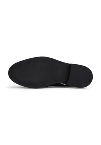 Semelle de chaussure noire avec grip texturé sur les zones des orteils et du talon, vue par le dessous sur fond blanc.