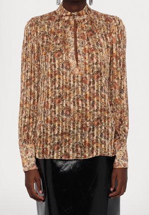Blouse fleurie à manches longues et col montant avec tissu plissé et petite ouverture en forme de goutte devant, associée à une jupe noire brillante.