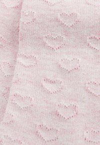 Helles rosa Strickgewebe mit einem strukturierten Muster aus kleinen Herzen, das weichen und glatten Aussehen hat und leicht unterschiedliche Fadenfarben aufweist.