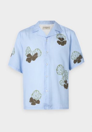 Camisa de manga corta en tela azul claro con patrones florales en verde y marrón oscuro. Cuello clásico con botones en la parte delantera.