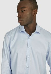 Lichtblauw overhemd van zacht stof met een geruit patroon, klassieke kraag en knoopsluiting. Tailored fit, lange mouwen.