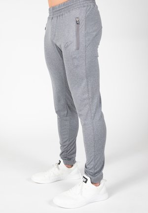 Grijze sportbroek van gestructureerd materiaal, met een slim fit, ritszakken en een elastische tailleband, gecombineerd met witte sneakers.