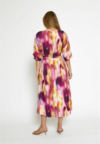 Langes, fließendes Kleid mit abstraktem Muster in Lila, Pink und Gelb. Es hat breite Ärmel und eine taillierte Taille, aus einem glatten, leichten Stoff.