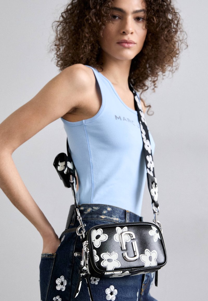 Μαύρη τσάντα ώμου με φλοράλ σχέδιο και ασημένιες λεπτομέρειες. Κατασκευασμένη από υλικό με υφή. Ο ιμάντας που ρυθμίζεται διαθέτει σχέδιο με λουλούδια.