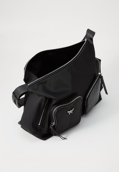 Black nylon shoulder bag with multiple zip pockets, featuring a smooth texture and silver hardware. One pocket has a subtle pattern accent.