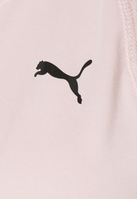 Un tessuto rosa chiaro presenta un logo Puma nero prominente che raffigura un gatto in salto. La superficie appare liscia con leggere rigature.