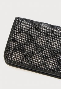 Μαύρο πορτοφόλι με σχεδιασμό υφασμάτινου πλέγματος, διακοσμημένο με μαύρες και διάφανες στρας σε λουλουδένιο μοτίβο. Περιμετρικά σε ομαλή μαύρη υφή.