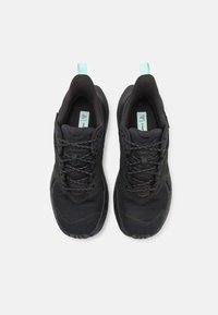 Pantofi sport negri cu un exterior texturat, panouri din plasă și accente reflective, dotati cu un tab de tragere verde mentă pentru o încălțare ușoară.