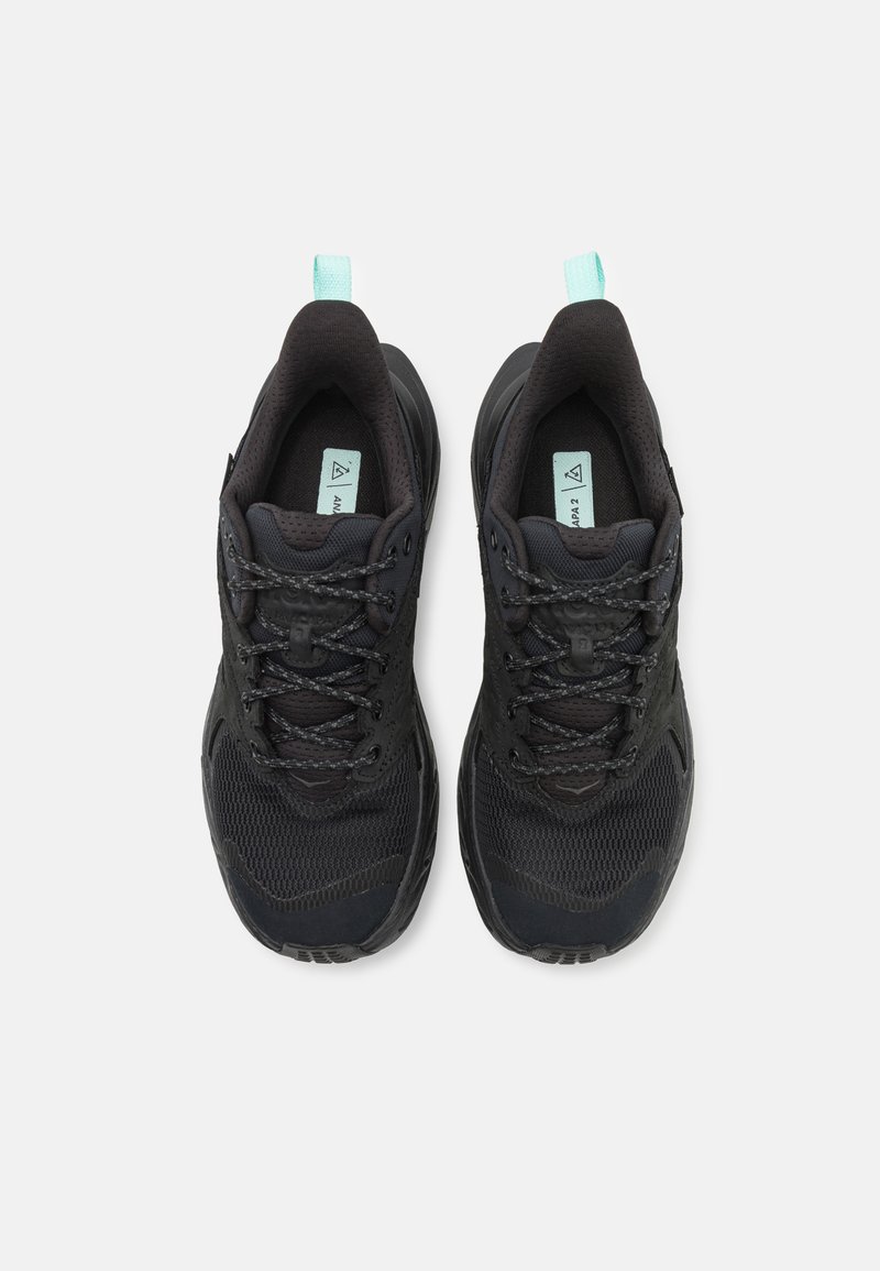Czarne buty sportowe z teksturowaną cholewką, siateczkowymi panelami i odblaskowymi akcentami, z miętowym uchwytem ułatwiającym zakładanie.
