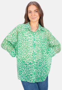 Green leopard print button-up shirt made of lightweight fabric, featuring a classic collar and relaxed fit, with rolled-up sleeves and button detailing.