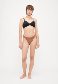 Zwarte v-hals bralette en een bruine high-waisted bikini onderkant gemaakt van gladde stof. De bralette heeft dunne bandjes en een naadloos ontwerp.
