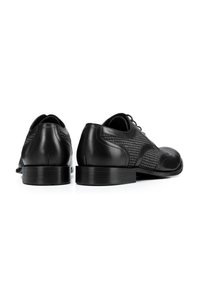 Zapatos de vestir de cuero negro con un patrón texturizado, punta redondeada y un acabado suave; cuentan con un tacón bajo y un diseño clásico de cordones.
