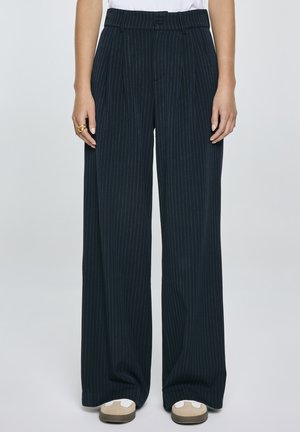 Pantaloni rigati blu scuro con vita alta, pieghe e gamba larga, realizzati in tessuto morbido. Presentano una chiusura con bottone in vita.