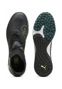 Zapatillas deportivas negras con un upper texturizado, acentos en verde neón y una suela con un patrón que presenta elementos de agarre en forma circular. Incluye cordones.