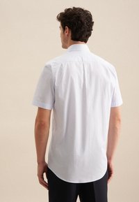 Camicetta a maniche corte con un tessuto azzurro chiaro e textured, colletto a punta e orlo curvo. Presenta un fit classico con pince posteriori.