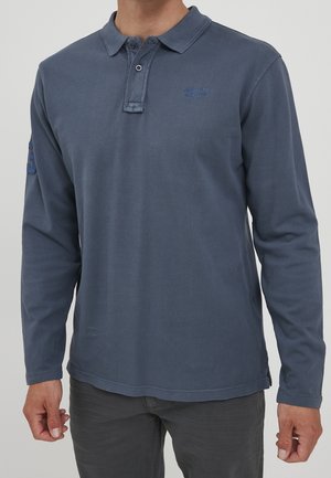 Polo a maniche lunghe in cotone blu scuro con finitura testurizzata. Presenta un colletto, una chiusura a due bottoni e un accento ricamato sul petto.