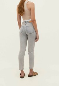 Vaaleansiniset korkeavyötäröiset farkut, joissa on slim fit -malli, viisi taskua ja takana nahkainen etiketti.