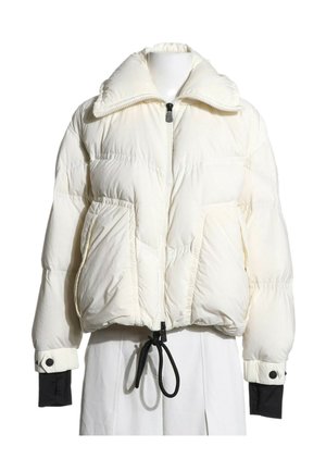 Chaqueta acolchada blanca con cuello alto, cremallera frontal, cordón en el dobladillo, bolsillos laterales y puños interiores negros en las mangas, sobre un maniquí.