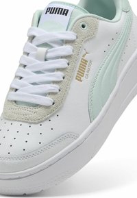 Bílé a světle mentolové tenisky Puma s bílými tkaničkami, perforovanou špičkou, semišovým panelem na šněrování a zlatým logem Puma CA Match na boku.