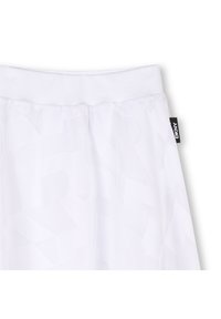 Pantalons de jogging blancs avec un design texturé, une taille élastique et une étiquette de logo DKNY sur le côté. Tissu doux et léger.