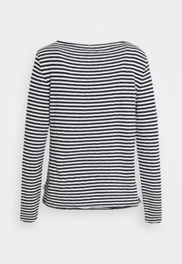 Camiseta de manga larga con un patrón de rayas en blanco y negro, escote ancho y textura suave, con el dobladillo ligeramente curvado en los lados.