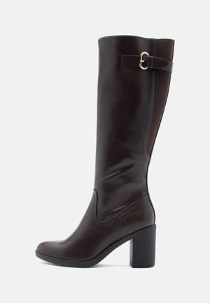 Brown leather knee-high boot with a square toe, chunky block heel, and elastic side panel. Features a decorative buckle at the top.