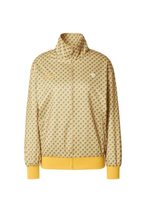 Sárga cipzáros dzseki ismétlődő kék madármintával, magas gallérral, oldalzsebekkel, valamint elasztikus mandzsettákkal és szegéllyel.