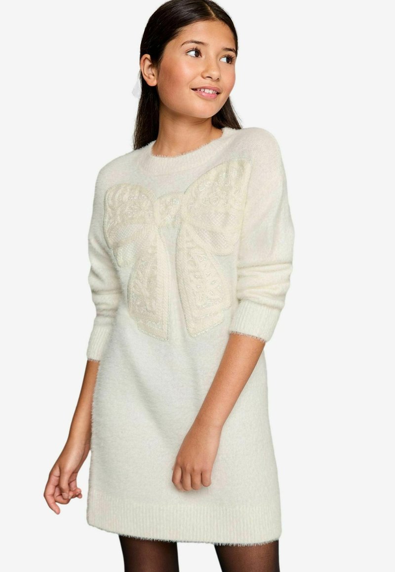 Hellbeiges gestricktes Kleid mit einem strukturierten, großen Schleifendekor auf der Vorderseite. Verfügt über gerippte Bündchen und einen gerippten Saum; weicher, flauschiger Stoff.