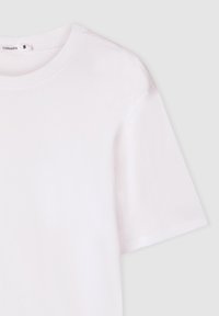 T-shirt a maniche corte, con scollo rotondo, in morbido cotone bianco. Presenta un colletto a costine e una vestibilità ampia senza motivi o dettagli visibili.