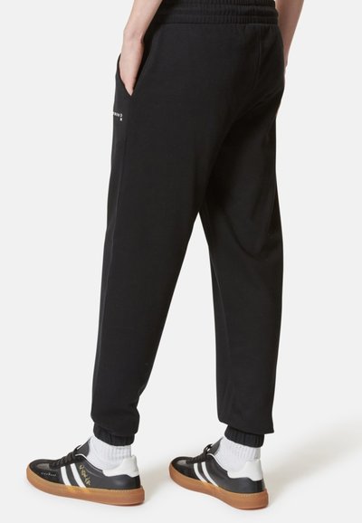 Pantaloni della tuta neri realizzati in tessuto morbido, con vita elastica, tasche laterali e una vestibilità affusolata e casual.