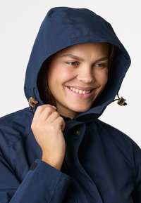 Giacca impermeabile navy con cappuccio, regolatore con cordino, chiusura frontale con bottoni e tessuto testurizzato. Presenta un design elegante e polsini aderenti.