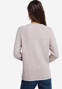 Maglione lavorato a maglia rosa chiaro con scollatura rotonda, maniche lunghe, orlo a costine e texture morbida. La vista posteriore mostra un tessuto liscio senza fantasie.