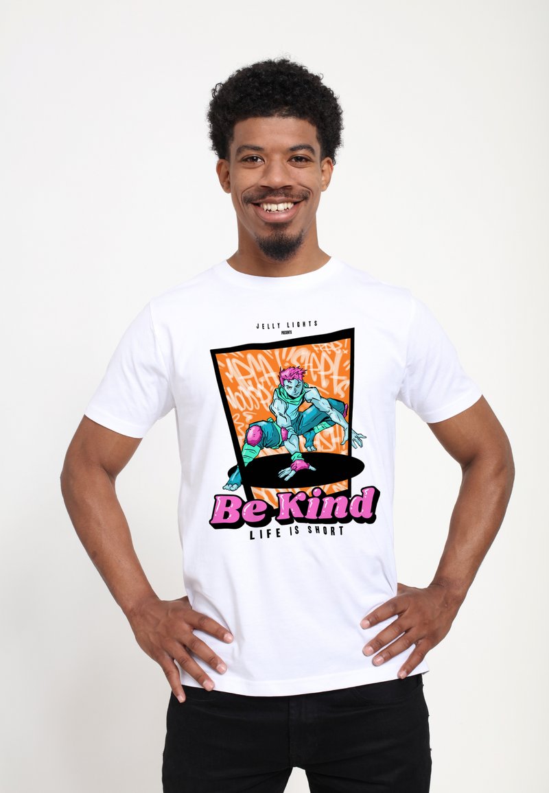 Bílý tričko s krátkým rukávem s barevným grafickým potiskem, na kterém je text "Buď laskavý" a ilustrace postavy v dynamické póze.