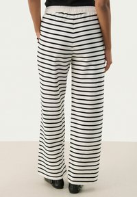 Pantalons large en noir et blanc à rayures, avec une taille élastique et un tissu doux et texturé.
