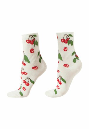 Chaussettes blanches aux chevilles avec un motif de cerise rouge et de feuille verte sur un tissu côtelé, vues de profil.